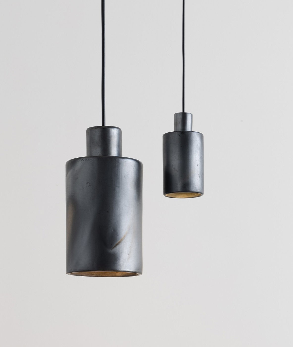 Two cylindrical pendant lights hanging against a plain background