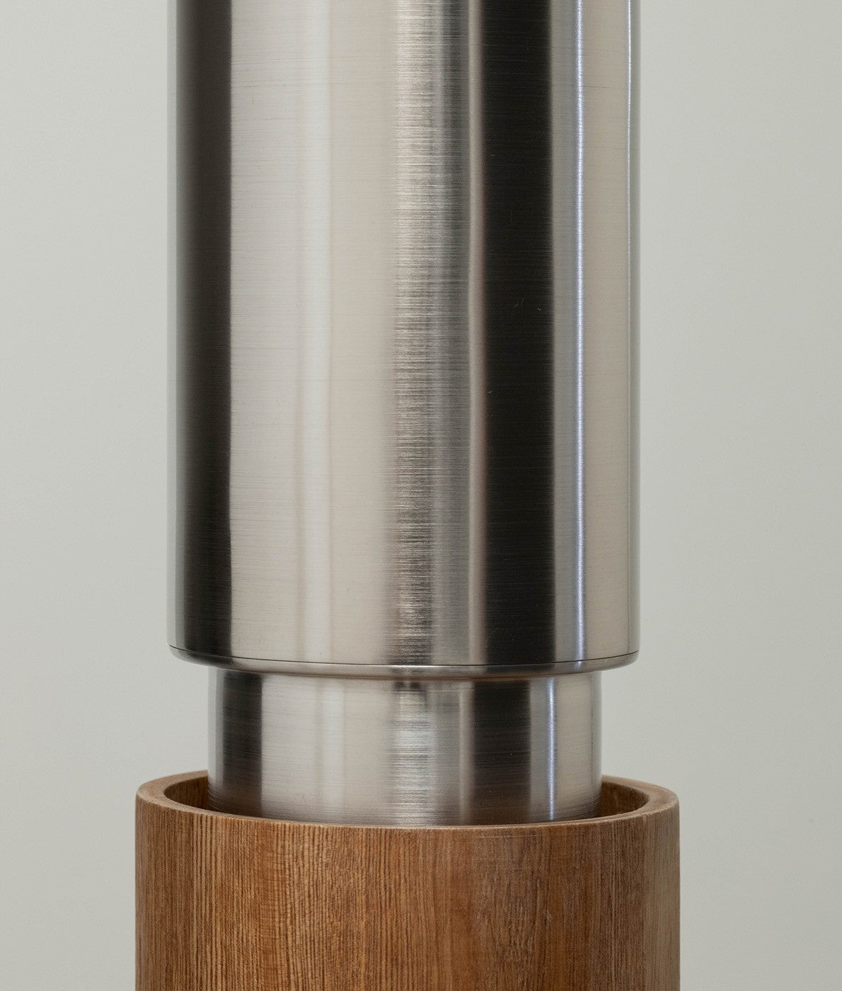 Close-up view of a pendant light featuring a stainless steel top and a rich wood base.