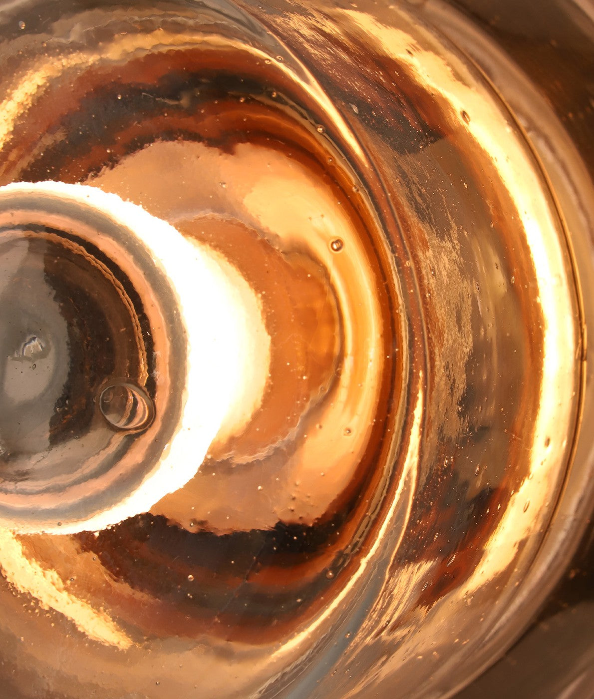 Close-up of glass with warm light reflections and intricate texture details.